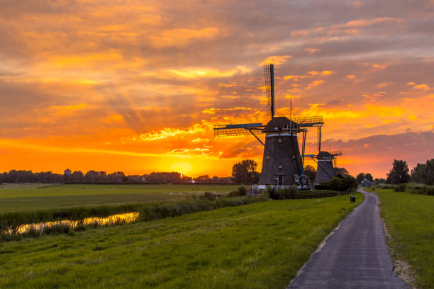 istock Wooden windmills in a row at orange sunset 1205000991