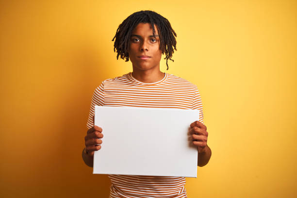 istock Afro american man with dreadlocks holding banner over isolated yellow background with a confident expression on smart face thinking serious 1205003713