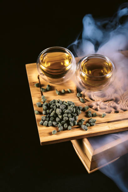 istock Chinese tea ceremony. Cups at tea board with hot green tea, milky oolong ginseng on black background 1205005208