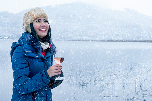 Asian woman drinking wine on snowy day