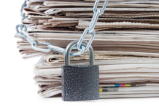 istock pile of newspapers with chains, on white 120500689