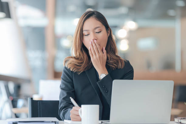 imprenditrice stanca e assonna che sbadiglia mentre lavora in un ufficio moderno. - yawning women drink coffee cup foto e immagini stock