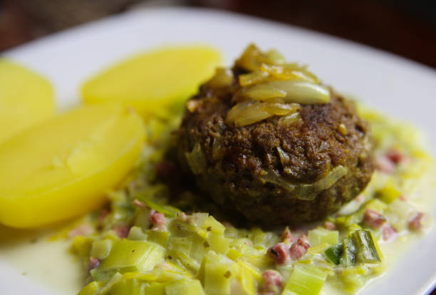 View on white plate with cooked potatoes, beef meatball, onions and leek vegetable