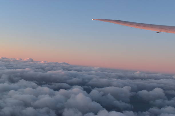 beautiful clouds on the sky with dramatic sunset light under aircraft wing, view from airplane window. - skeg imagens e fotografias de stock