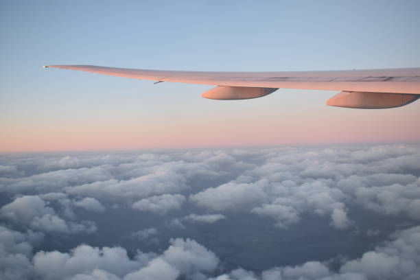 beautiful clouds on the sky with dramatic sunset light under aircraft wing, view from airplane window. - skeg imagens e fotografias de stock