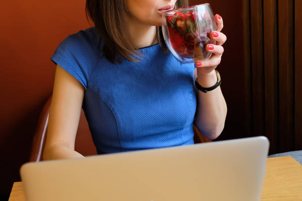 istock Girl in a cafe drinks tasty tea with berries while working on a laptop. 1205011778