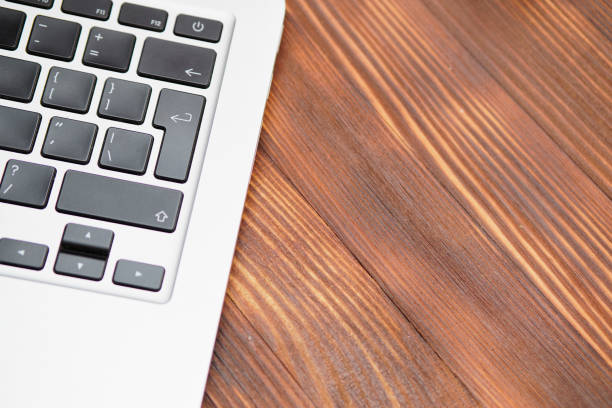 A top-down view of a rustic wooden desk featuring a black laptop, a cup of coffee on a coaster, and small potted succulents. The empty space in the center provides room for text or design elements, making it ideal for work, productivity, and minimalist workspace concepts.