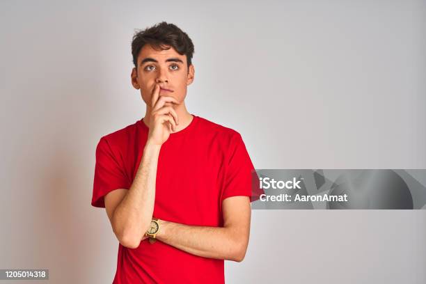 Teenager Boy Wearing Red Tshirt Over White Isolated Background With Hand On Chin Thinking About Question Pensive Expression Smiling With Thoughtful Face Doubt Concept Stock Photo - Download Image Now