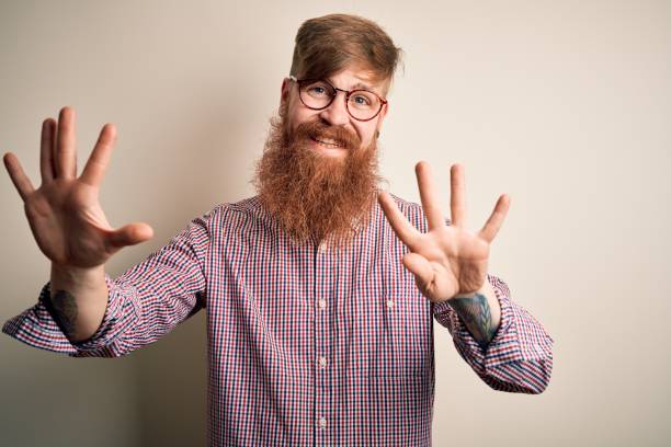 istock Handsome Irish redhead business man with beard wearing glasses over isolated background showing and pointing up with fingers number nine while smiling confident and happy. 1205015640