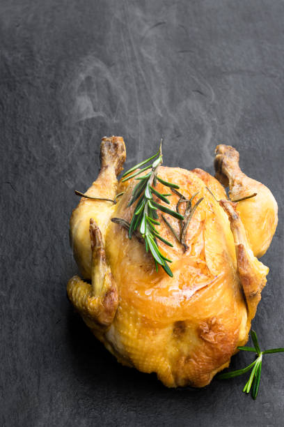 istock Roasted poussin with rosemary on black stone background 1205017721