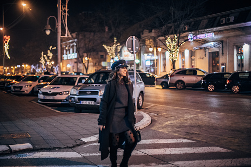 Fashionable young woman with hat is walking on the street.