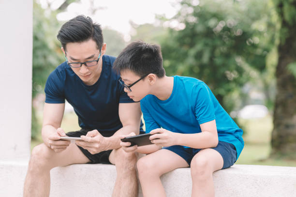 istock an sian chinese man playing online mobile game with his son 1205019307