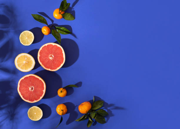 Composition with citrus fruits on a bright blue background. Bright light, contrasting shadows.