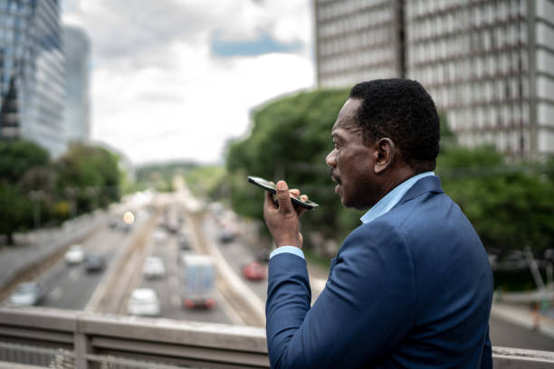 mature businessman talking on mobile phone while walking on the street - conference phone imagens e fotografias de stock