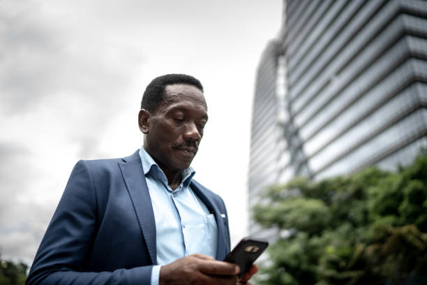 istock Mature businessman walking and using mobile phone at city 1205026973