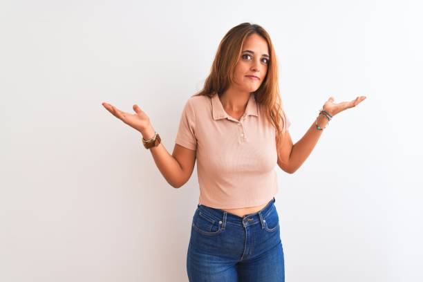 istock Young redhead woman stading over white isolated background clueless and confused expression with arms and hands raised. Doubt concept. 1205028894