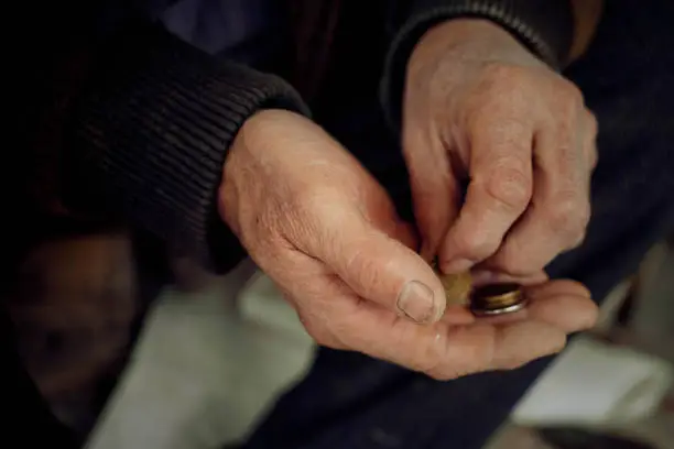 Photo of The hands of an elderly man consider small things.