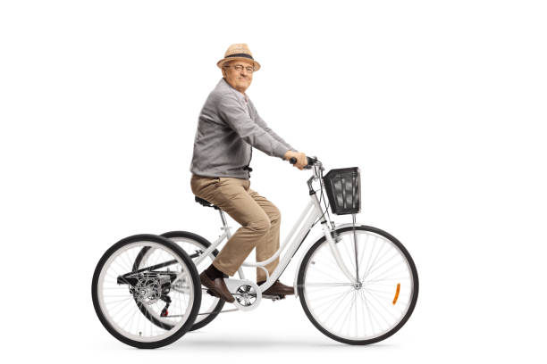 istock Elderly man riding a white tricycle and smiling at the camera 1205030001