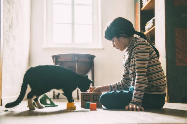 istock girl playing with black cat on the floor 1205030207