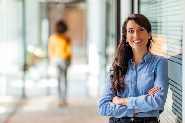 Young mixed race businesswoman smiling to camera One Happy Pretty Business Woman Standing in Hall and looking at camera with smile. one woman only stock pictures, royalty-free photos & images