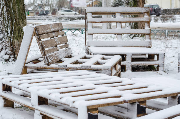 Stack of wooden logs covered with fresh snow on white background (cut out).