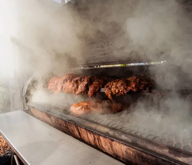 Photo of Large barbecue smoker grill at the park. Meat prepared in barbecue smoker.