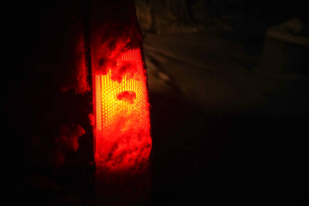 istock POV driving on snow covered road at night, first snow falling. Stoplight illuminates everything in red. 1205032059