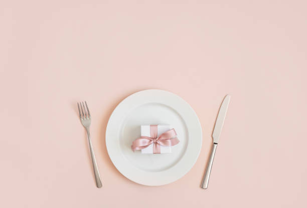 istock Festive table setting with a gift in a plate on a pink background. Romantic or wedding dinner. Valentines day or mothers day background. 1205032817