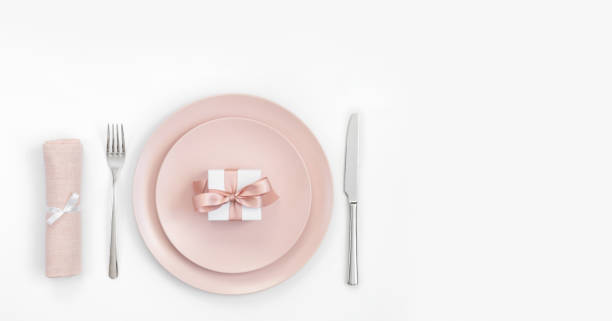 istock Pink table setting with a gift in a plate, napkin and cutlery on a white background. Romantic or wedding dinner. Valentines day background. 1205032852