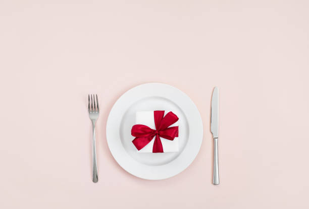 istock Festive table setting with a red gift in a plate on a pink background. Romantic or wedding dinner. Valentines day or mothers day background. 1205033085