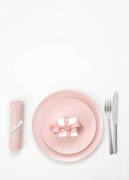 istock Pink table setting with a gift in a plate, napkin and cutlery on a white background. Romantic or wedding dinner. Valentines day background. 1205033272
