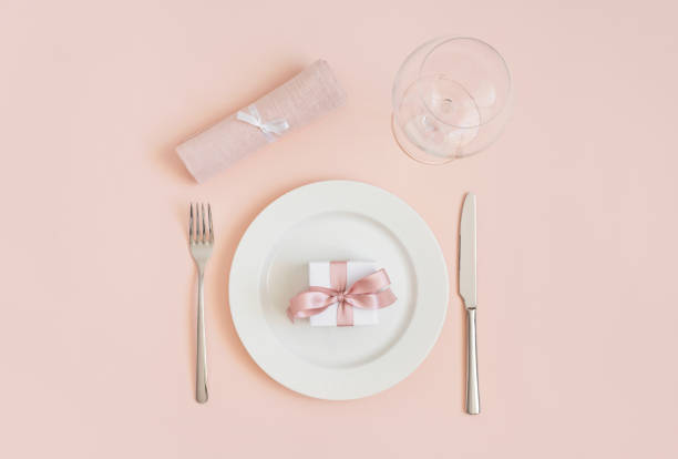 istock Festive table setting with a gift in a plate and cutlery on a pink background. Romantic or wedding dinner. Valentines day or mothers day background. 1205033488