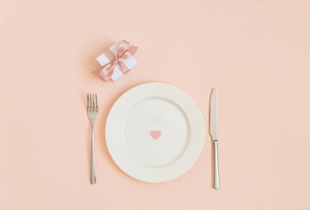 istock Festive table setting with a heart in a plate and a gift on a pink background. Romantic or wedding dinner. Valentines day or mothers day background. 1205033538