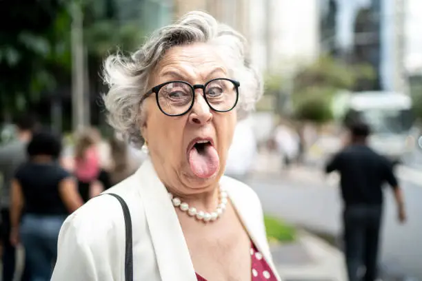 Senior businesswoman sticking out tongue at city