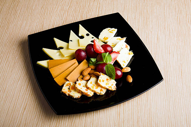 Cheese and berry at black plate stock photo