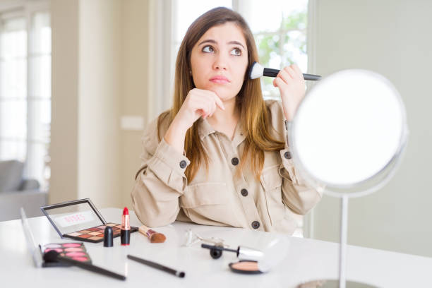 istock Beautiful young woman using make up cosmetics applying color using brush serious face thinking about question, very confused idea 1205036924