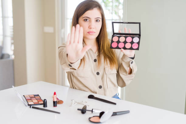 istock Beautiful young woman using make up cosmetics applying color from palete with open hand doing stop sign with serious and confident expression, defense gesture 1205037016