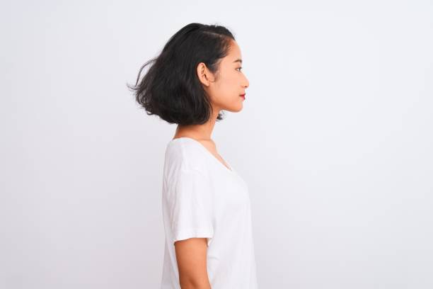 young chinese woman wearing casual t-shirt standing over isolated white background looking to side, relax profile pose with natural face with confident smile. - serious women asian ethnicity human face imagens e fotografias de stock