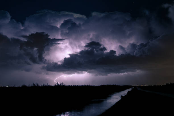 lightning bolt from a huge thunderstorm hits the ground - summer landscape flash imagens e fotografias de stock