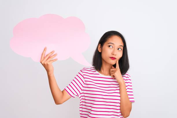 istock Young chinese woman holding cloud speech bubble standing over isolated white background serious face thinking about question, very confused idea 1205039107