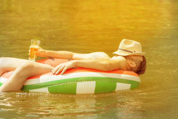 istock man with a drink in the pool on an inflatable mattress 1205039879