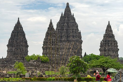 asian Chinese woman with her son walking on the grass with prambanan temple in the background