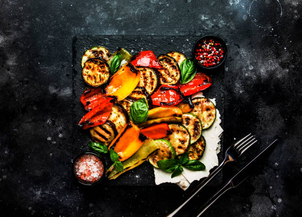 istock Grilled multicolored vegetables, aubergines, zucchini, pepper with green basil on serving stone board on black background, top view 1205057313