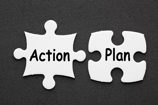 The words Action Plan on two matching puzzle on black background. Business concept