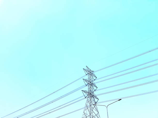 Low Angle View of High Voltage Towers and Power Lines Against Clear Blue Sky