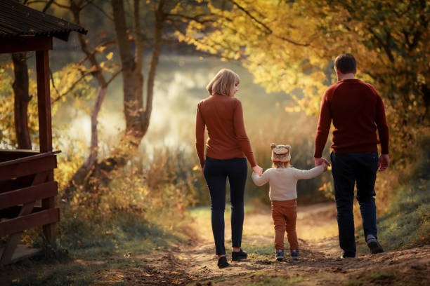 Family holiday together. Three Moms Father, and Daughter in The Autumn Forest On the Evening Walk. Walking through the woods