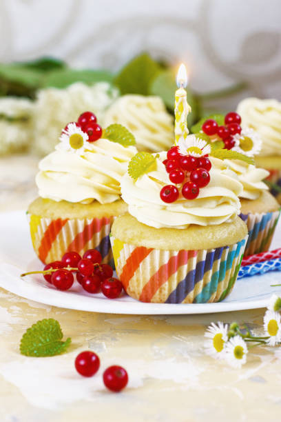 istock Gentle, festive cupcake with cream and berries nd a candle a light background 1205058597