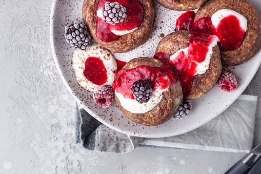 Chocolate cottage cheese pancakes or fritters with sour cream and frozen berries (raspberry and blackberry). Traditional Ukrainian and Russian cuisine. Syrniki. Healthy and diet breakfast or dessert.