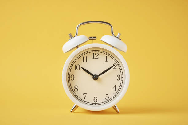 istock White retro alarm clock on the yellow background with copy space. Time concept 1205063609