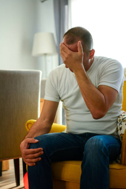 istock Sad man sitting on armchair at home, vertical. 1205063665